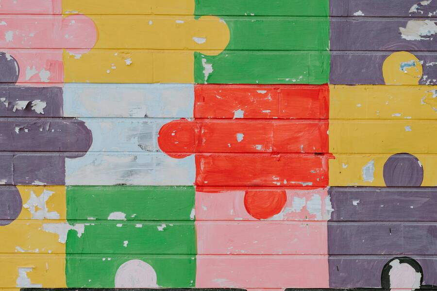 A brick wall painted with a puzzle with multicolored pieces